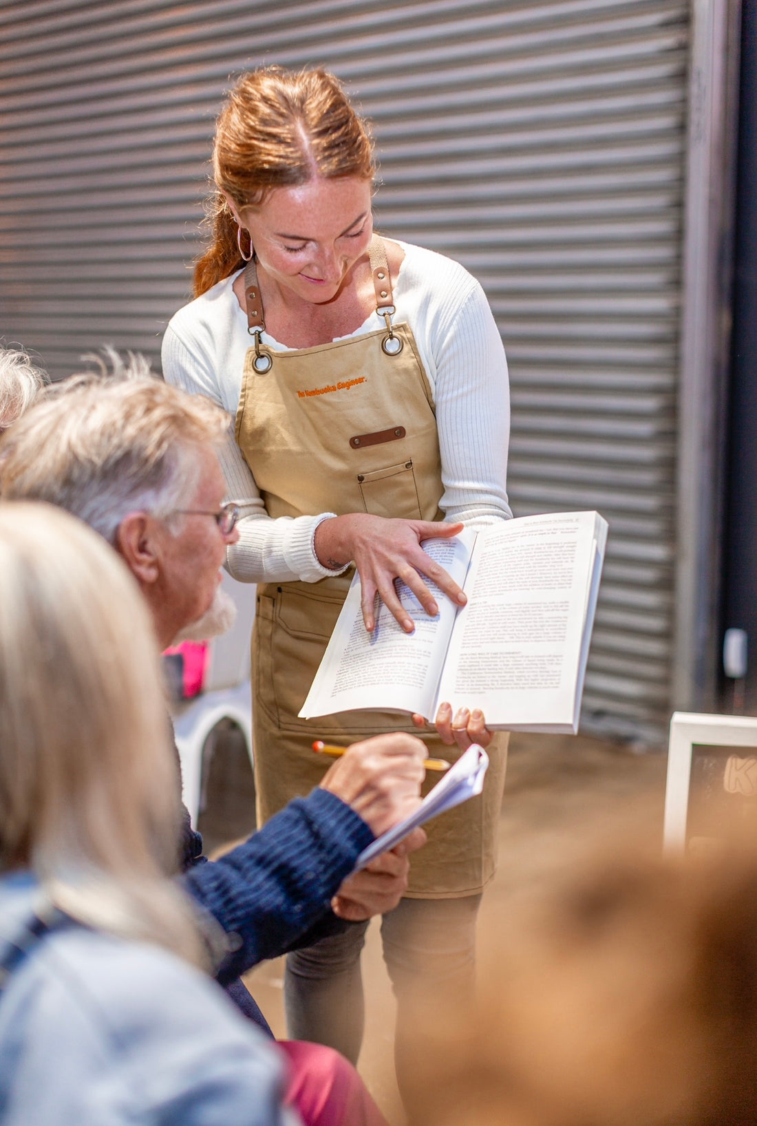 Our proud founder Hebe, showing a brewing workshop student a page in a kombucha brewing help book during a brewing workshop - boochacha