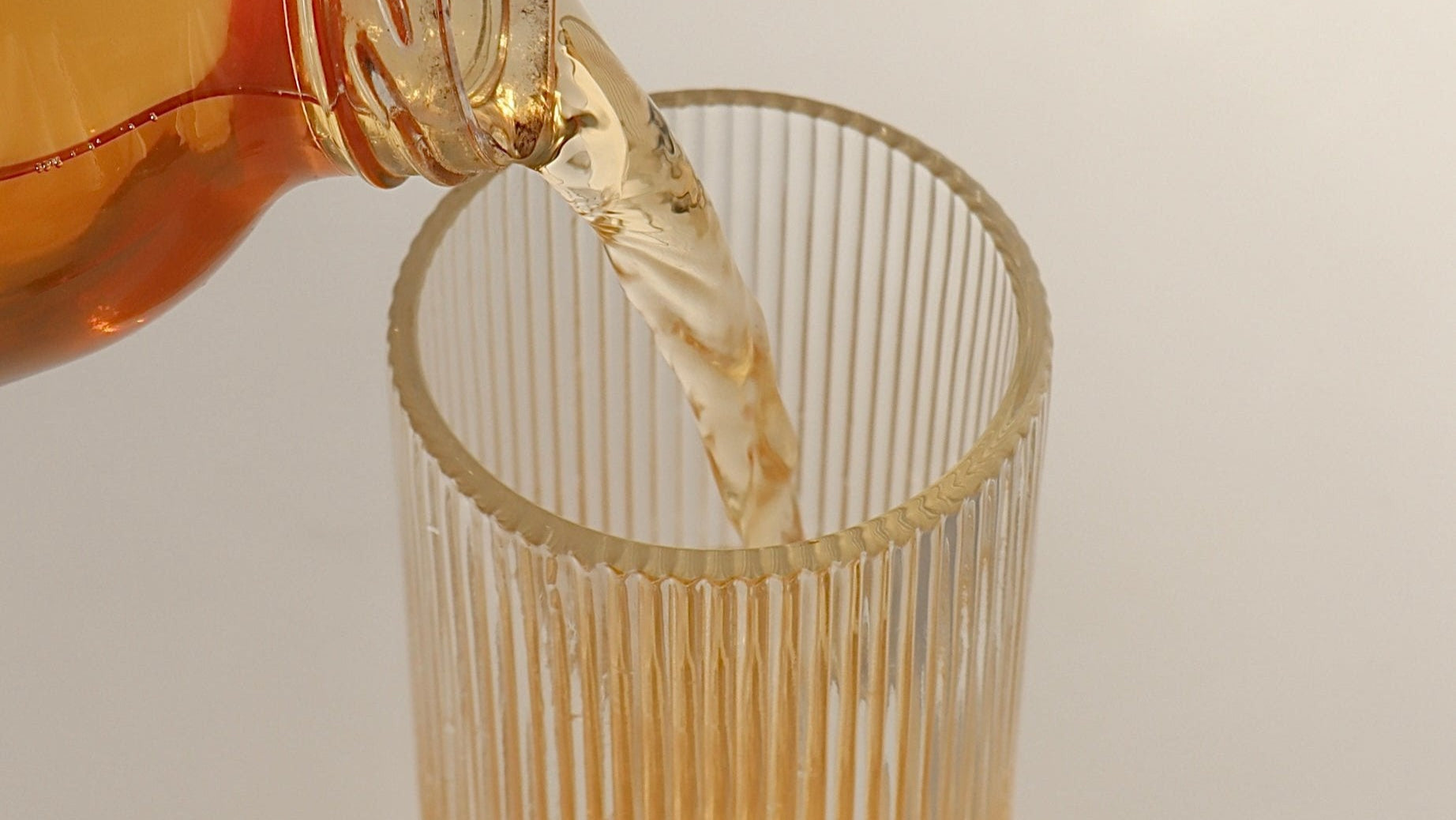 Photo of a delicious, fresh, raw and totally natural glass of kombucha being poured into a fancy glass, against an aesthetic background with nice shadows being cast - boochacha