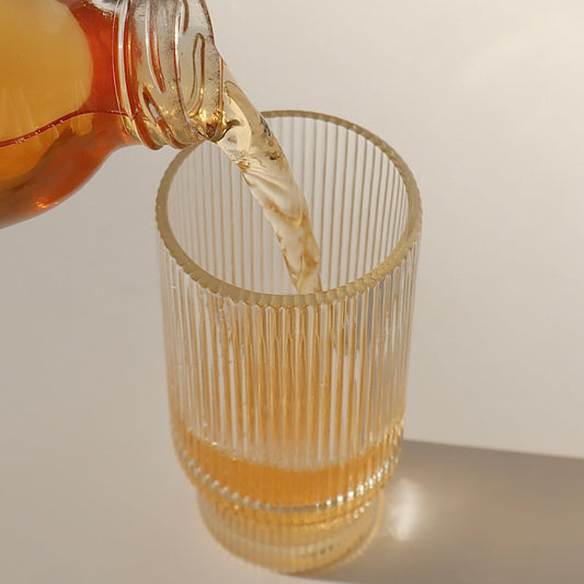 Photo of a delicious, fresh, raw and totally natural glass of kombucha being poured into a fancy glass, against an aesthetic background with nice shadows being cast - boochacha